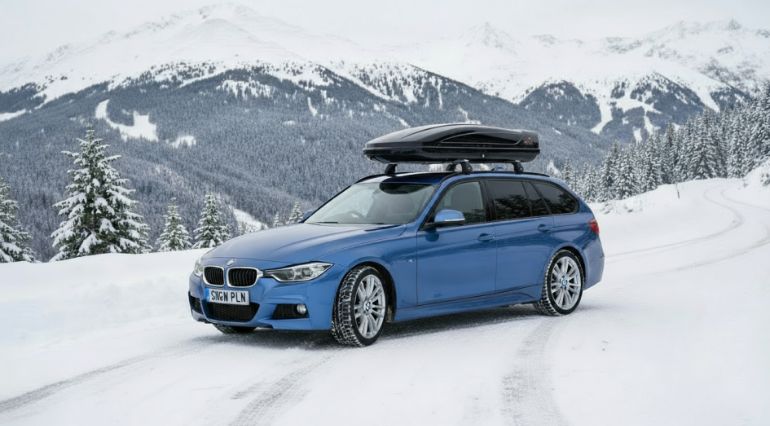 Blue BMW estate on snow covered mountain