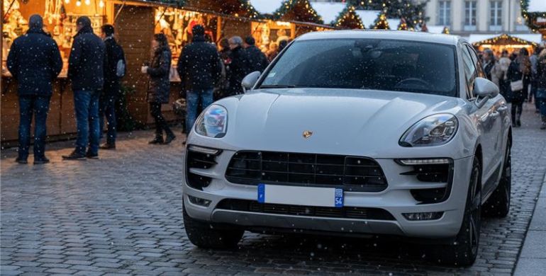 Porsche parked outside a snowy European market 