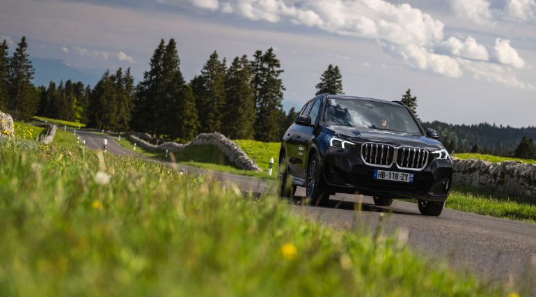 A BMW iX1 driving along a country road