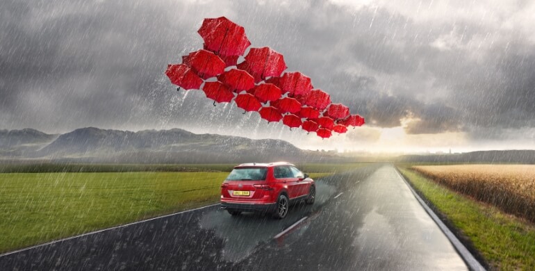 SUV in rain with umbrellas sheltering it
