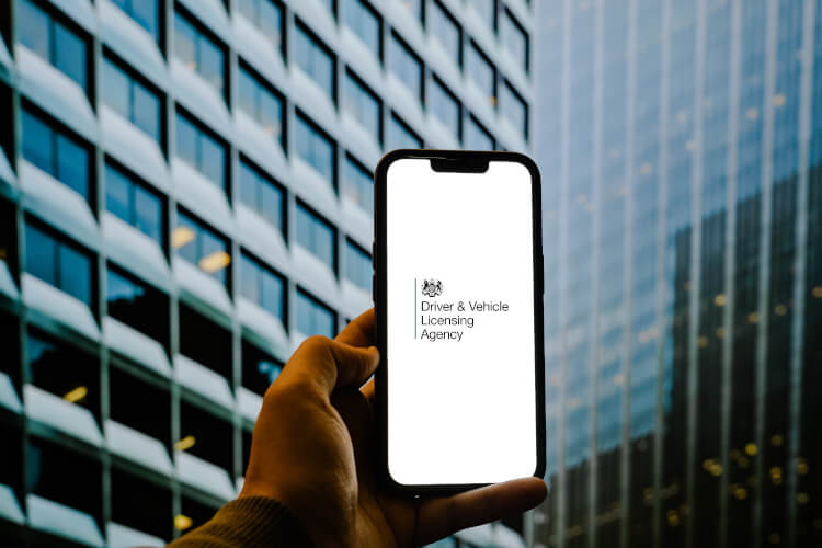 A phone with the UK Driver & Vehicle Licensing Agency logo displayed