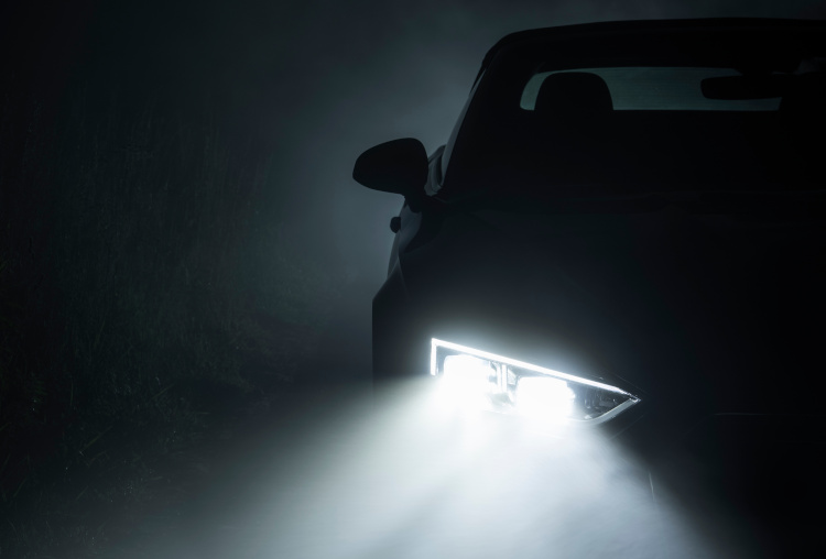 A car's fog light on in the dark fog