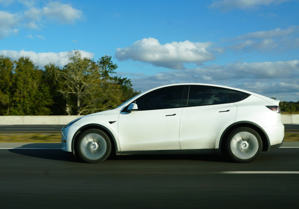 White Tesla Model Y driving along a motorway on a sunny day